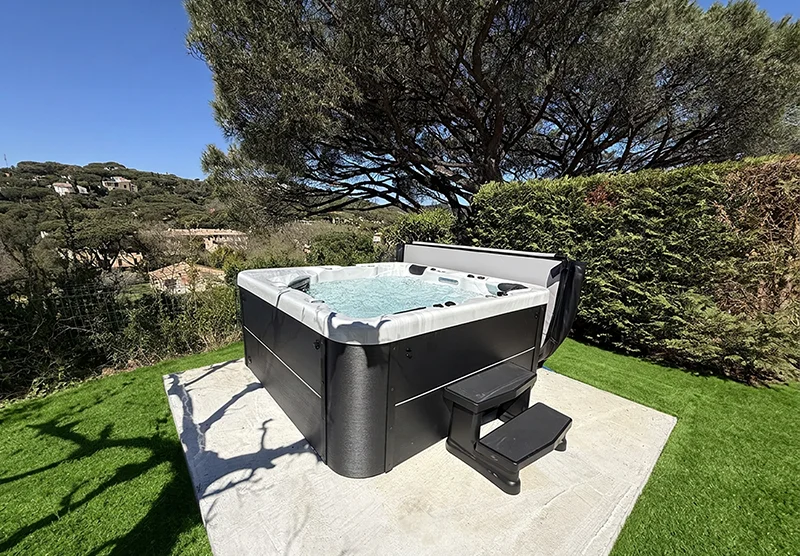 Spa Napoli New 5 places avec éclairage LED et chromothérapie sur une dalle au milieu d’une pelouse à La Croix-Valmer