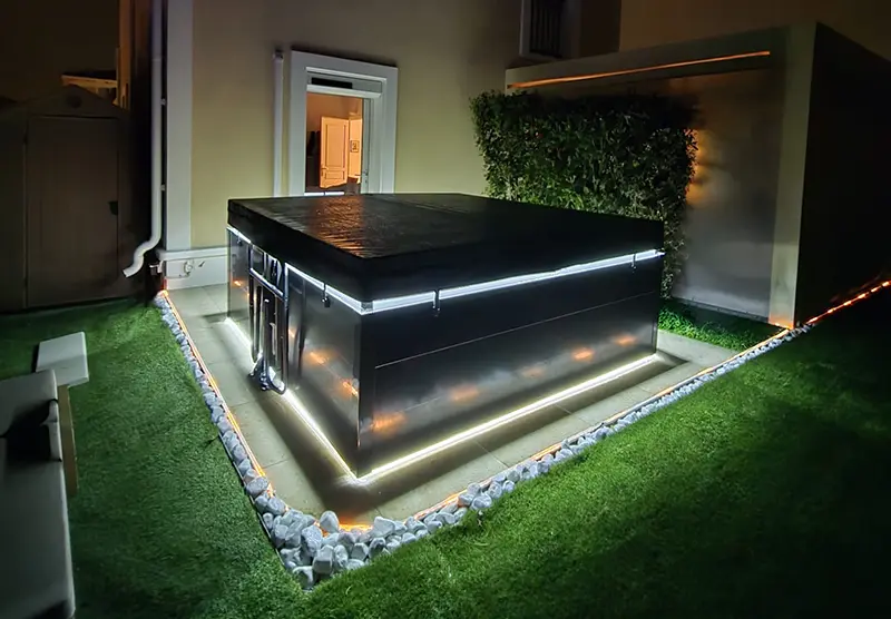 Dans le Var, devant une villa moderne, un spa recouvert de sa couverture isotherme. Deux rampes d'éclairage LED illuminent la nuit