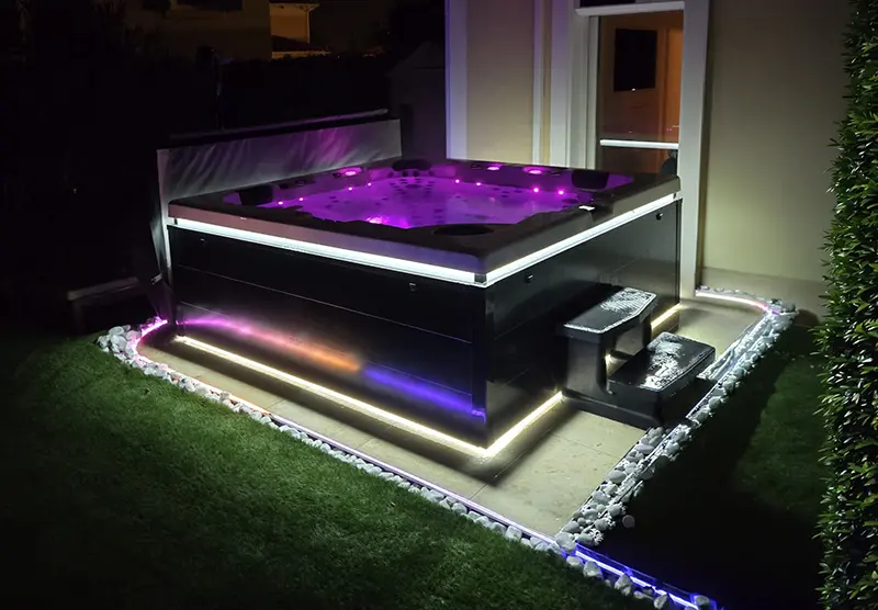 Spa design dans la nuit, avec 2 lignes d'éclairage LED extérieur et luminothérapie intérieure qui donne à l'eau une couleur violet