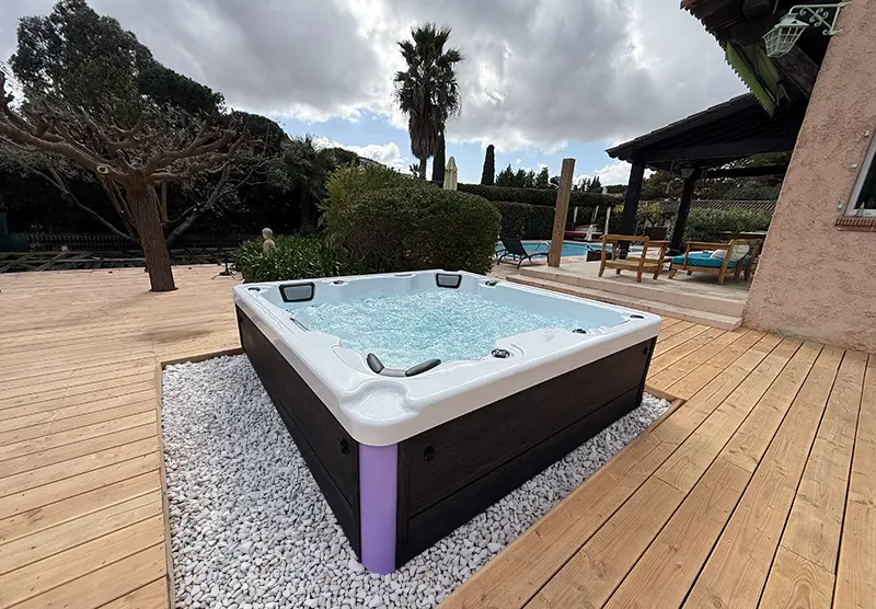 Un spa 6 places Amalfi de Giovanni Riboli posé sur une terrasse en bois clair devant une maison provençale avec piscine à Saint-Raphaël