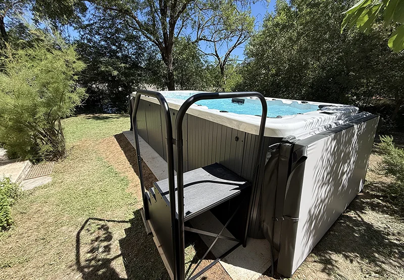 Spa de nage IR 5.0 installé dans un jardin naturel à Tourves avec marches d’accès et végétation provençale autour du bassin