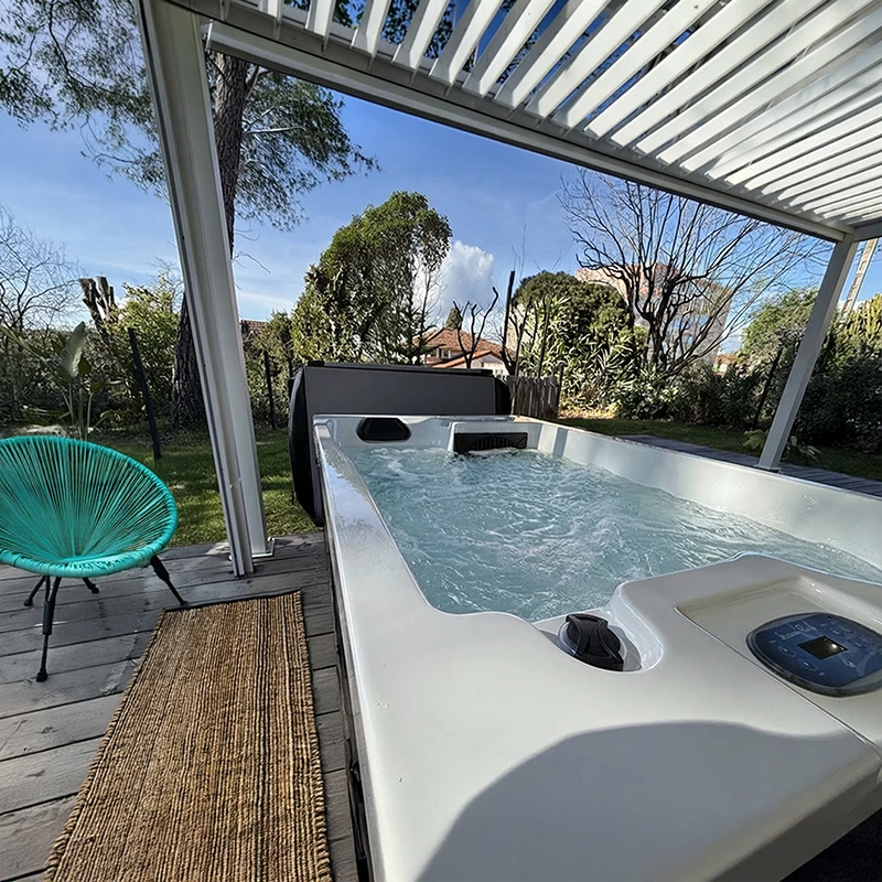 Spa 2 places allongées de la gamme Relax ouvert, installé sur une terrasse en bois sous une pergola bioclimatique design dans un rez-de-chaussée d'appartement au Cannet