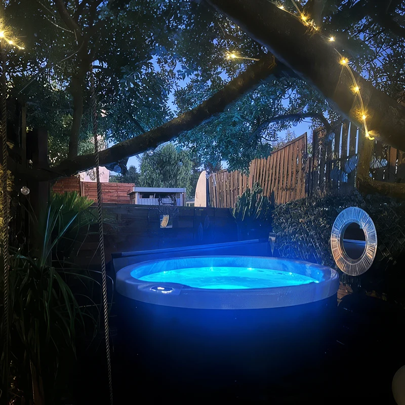 Spa rond 5 places modèle Rimini ouvert, avec éclairage LED bleuté et guirlandes lumineuses, sur une terrasse de nuit à Grasse